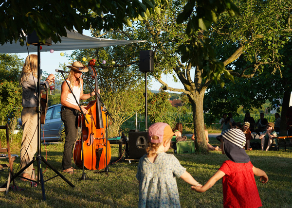 KI generiert: Ein Freiluftkonzert mit Musikern und Kindern, die tanzen.