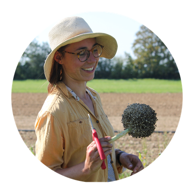 Eine Piluweri-Mitarbeiterin hält eine Dolde vom Lauch in der Hand.