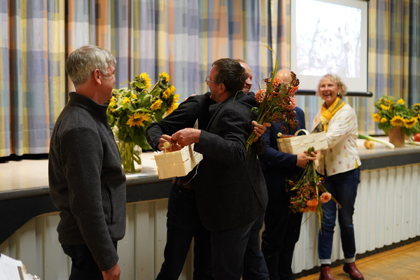KI generiert: Menschen in festlicher Zeremonie mit Blumen und Geschenkkörben, fröhliche Atmosphäre.