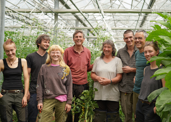 KI generiert: Eine Gruppe von Menschen steht lächelnd in einem Gewächshaus mit Pflanzen.