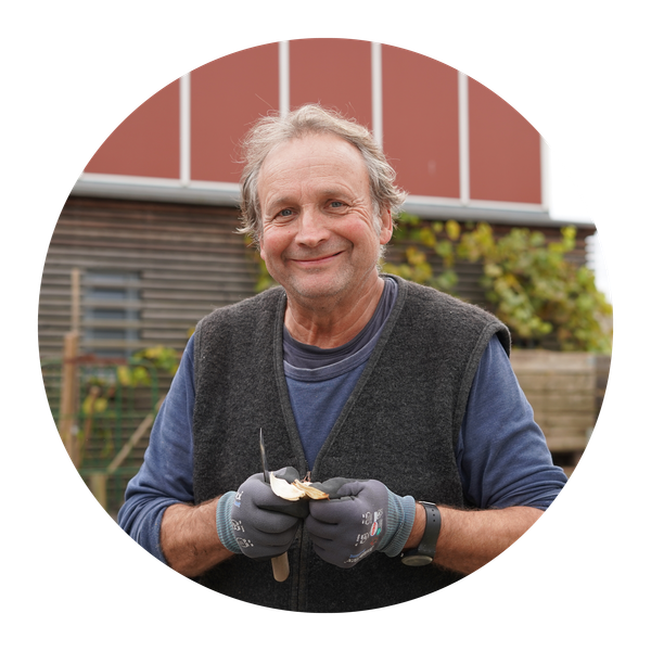 KI generiert: Ein Mann lächelt in die Kamera, während er mit einem Messer eine Kartoffel schält.