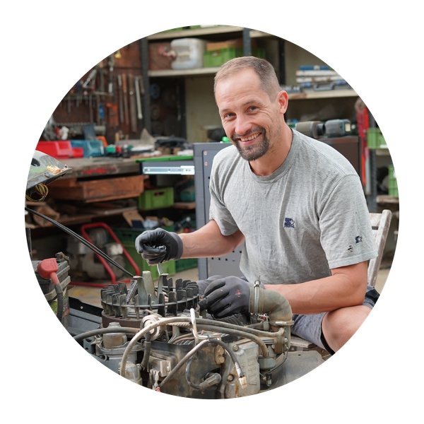 KI generiert: Ein Mann arbeitet lächelnd an einem Motor in einer Werkstatt.