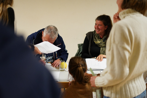 KI generiert: Personen bei einer Besprechung, einer signiert ein Dokument. Text: "Bubble Juice".