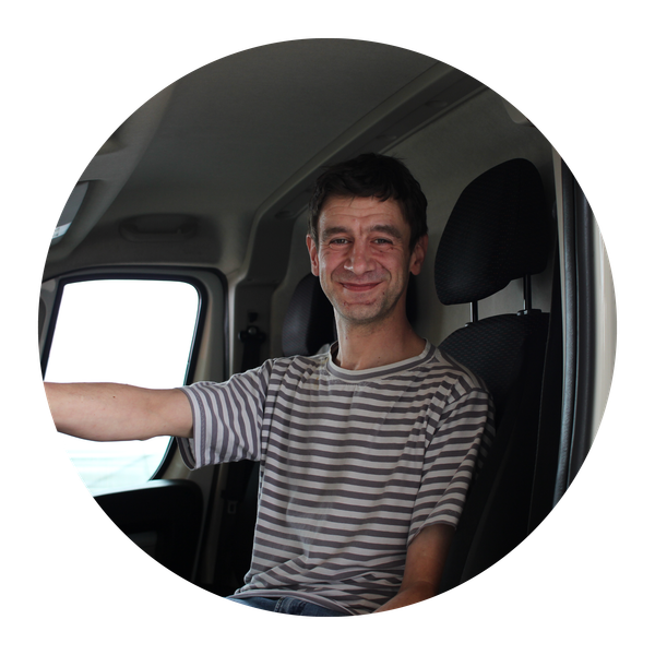 KI generiert: Ein Mann in gestreiftem Shirt sitzt lächelnd in einem Auto.