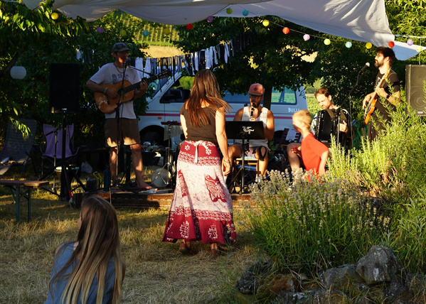 KI generiert: Eine Band spielt draußen auf einer Gartenbühne; Zuschauer tanzen.