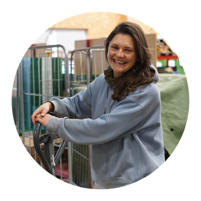 KI generiert: Eine Person in einem Lager lächelt und lehnt an einem Handhubwagen.