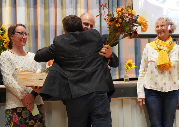 KI generiert: Menschen bei einer Feier; eine Person überreicht Blumen und ein Geschenk.