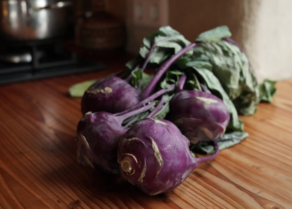 Mehrere blaue Kohlrabi liegen auf einer Küchentheke.