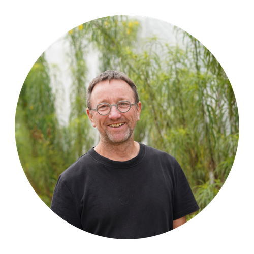 Porträt von Horst Ritter, einem unserer Gründer, vor grünen Büschen. 