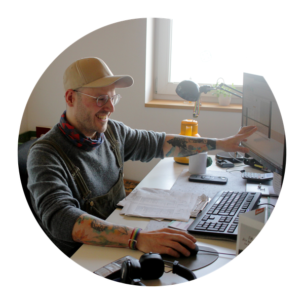 KI generiert: Eine Person arbeitet lächelnd an einem Schreibtisch mit Computer und Zubehör.