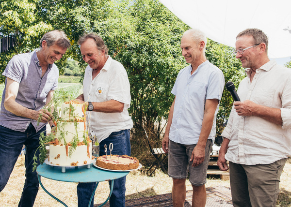 KI generiert: Vier Männer feiern im Freien mit einer pflanzenverzierten Torte. Auf einer Torte steht die Zahl 30.