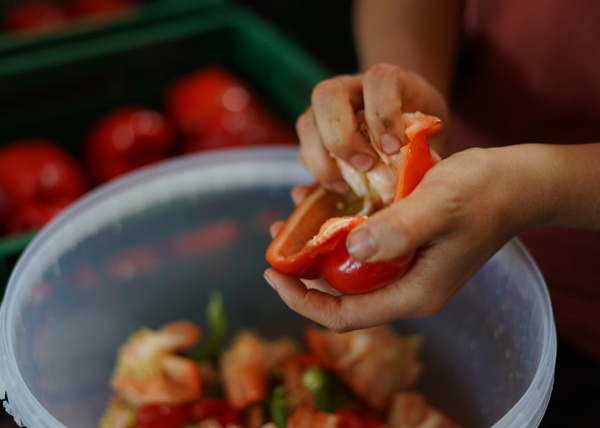 KI generiert: Eine Person putzt rote Paprika über einer Schüssel.
