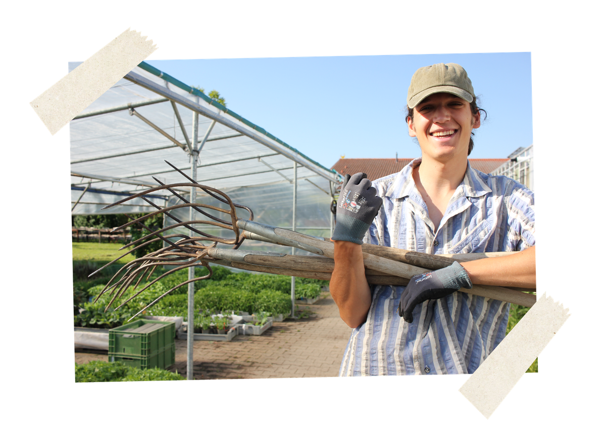 KI generiert: Ein Gärtner mit Heugabeln steht lächelnd vor einem Gewächshaus.