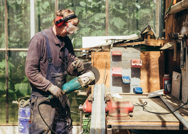 KI generiert: Eine Person arbeitet konzentriert mit einem Winkelschleifer in einer Werkstatt.